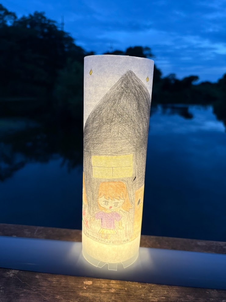 夕暮れの大川を背景に灯りがともった手描きの絵とうろう
