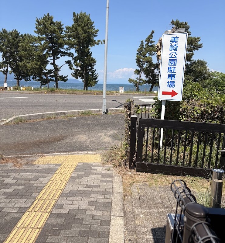 美崎公園駐車場の案内看板と道路の向こうに見える琵琶湖