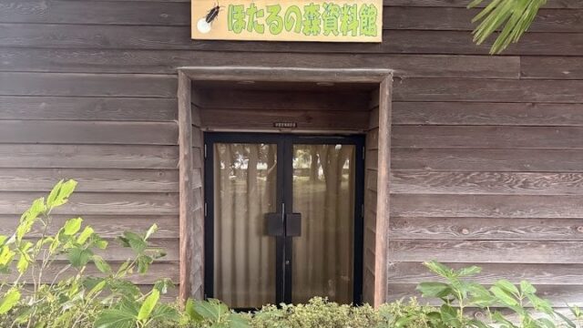 守山市民運動公園内にある「ほたるの森資料館」の入口。木造の建物を緑が囲んでいる。