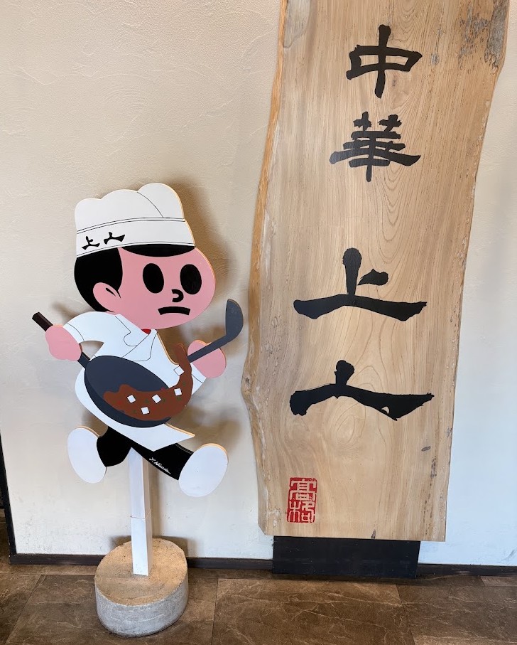 中華 上上の店内に飾られた木製看板と中華鍋を持ったキャラクター