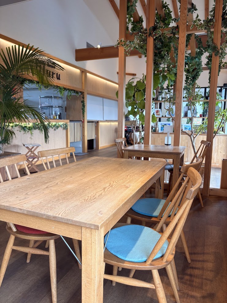 木製のテーブルと椅子、観葉植物が配置されたストロベリーファクトリーの店内
